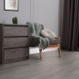 ML-Design Vinylboden Eiche Grau, selbstklebend, als Bodenbelag im Raum mit Kommode und Sessel.