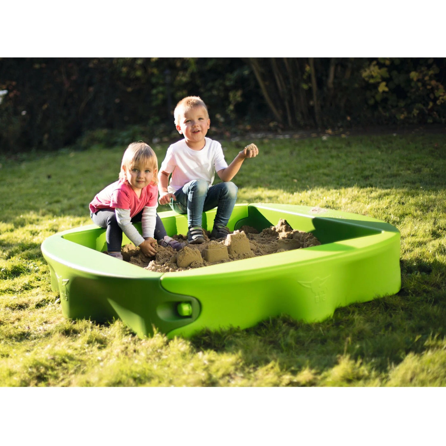 Grüner BIG Sandkasten Sandy mit zwei spielenden Kindern im Garten. Abdeckung vorhanden.