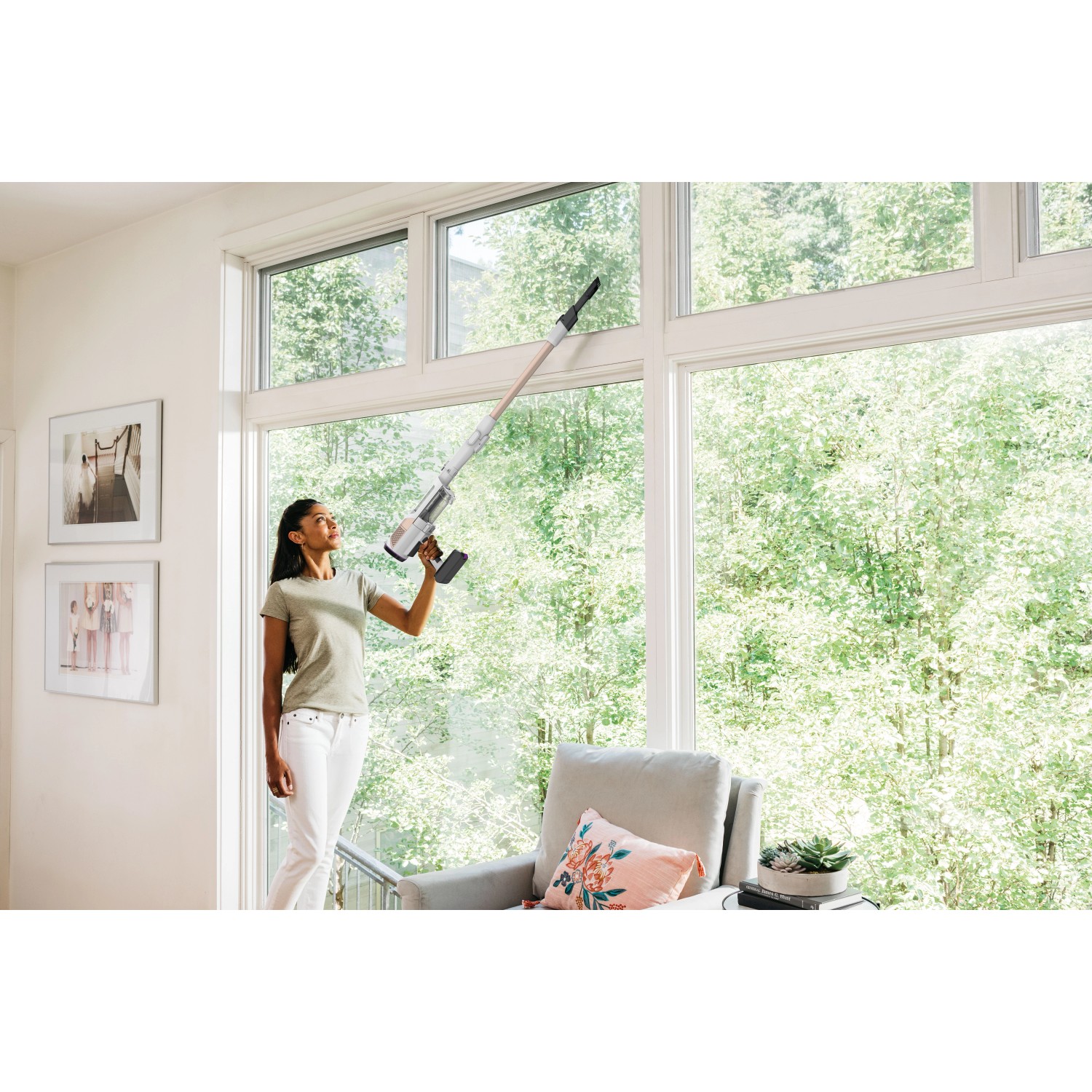 Frau reinigt Fenster mit Shark Detect Clean & Empty Akku-Staubsauger.