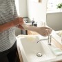 Person zieht Vileda Einweghandschuh Natural Latex Extra Long an Spüle an.