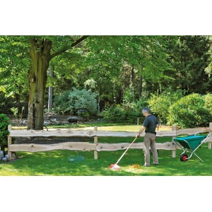 Mann harkt Laub vor einem T & J Zaunbrett Matteo Bonanza Eiche im Garten.