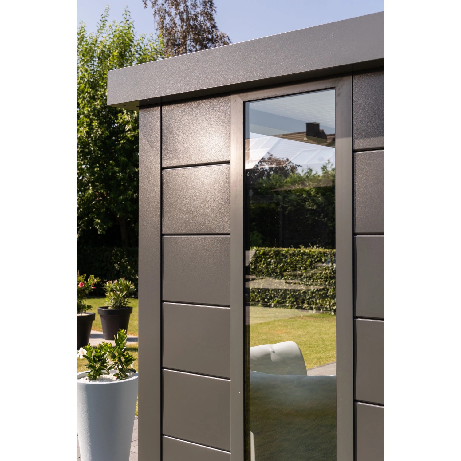 Modernes, graues Gerätehaus Classico Lounge XL mit Fenster und weißen Ecken im Garten.
