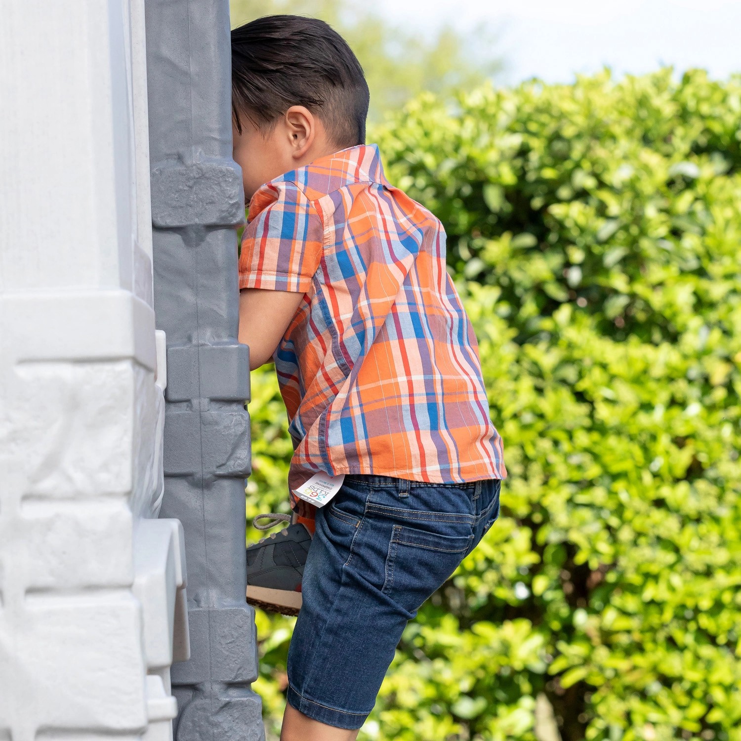Kind klettert an Step2 Spielhaus Adventures mit Rutsche im Garten hoch.