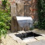 Ubbink Nevada LED Wasserfall aus Edelstahl im Garten mit Teichbecken und Dekoration.