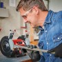 Mann schleift Metall mit Einhell Doppelschleifer TC-BG 150. Schleifmaschine mit Funkenschutz.