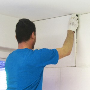 Mann montiert Kalziumsilikatplatte zur Schimmelsanierung an Wand.