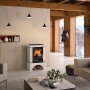 Justus Kaminofen Bavaria Ahorn Weiß mit Sockel (7 kW) im Wohnraum mit brennendem Feuer.