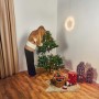 Frau schmückt grüne Kunsttanne Nagano (150 cm) mit Weihnachtsdeko. Künstlicher Weihnachtsbaum im Wohnzimmer.