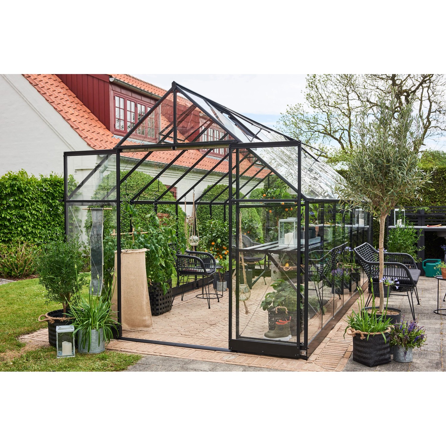 Schwarzes Halls Gewächshaus Qube+ 816 mit 13 m² Fläche im Garten.