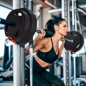 Frau trainiert mit schwarze SPORTNOW Hantelscheiben (7.5kg & 5kg) an einer Hantelstange im Fitnessstudio.