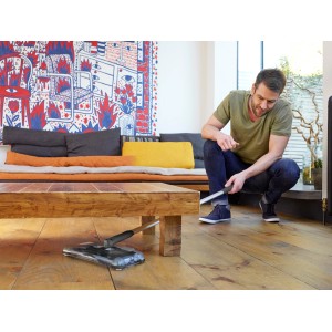 Black+Decker Akku-Kehrbesen PSA215B unter Tisch, Mann bedient den Bodenstaubsauger.