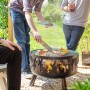 Buschbeck Feuerkorb Wildfire mit Grillfunktion im Einsatz mit Personen beim Grillen.