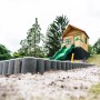 Axi Spielhaus Max mit Rutsche, Leiter und Sandkasten in Braun/Grün. Spielturm im Comic-Stil für Kinder.