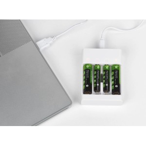 Batterie-Ladegerät mit USB und vier Akkus (2xAA, 2xAAA) beim Laden am Laptop.