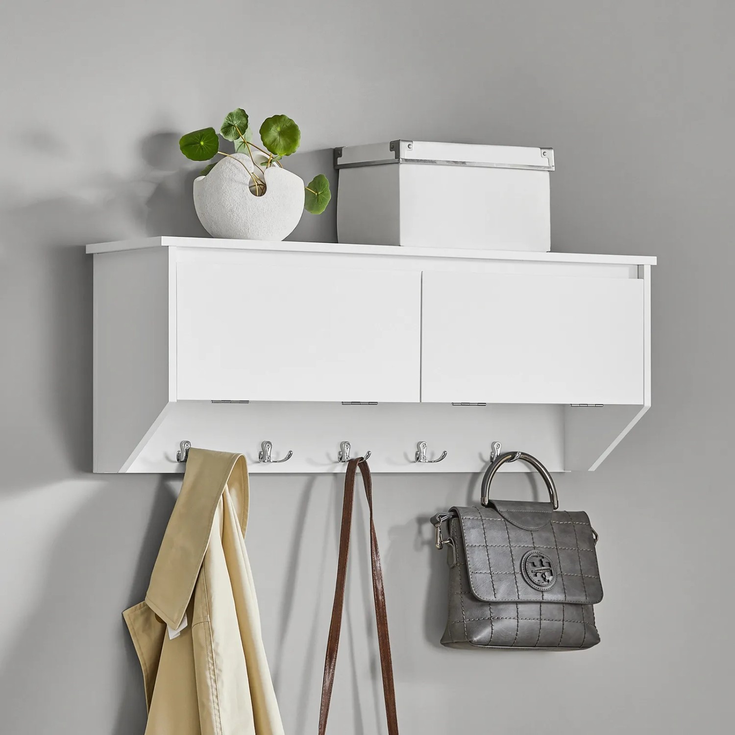 Weiße SoBuy Wandgarderobe mit 2 Klappen, 5 Haken und Accessoires an grauer Wand.