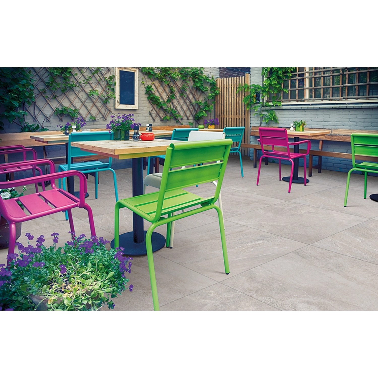 Verlegte Diephaus Quarz Terrassenplatten 60x60 cm auf einer Terrasse mit bunten Stühlen.