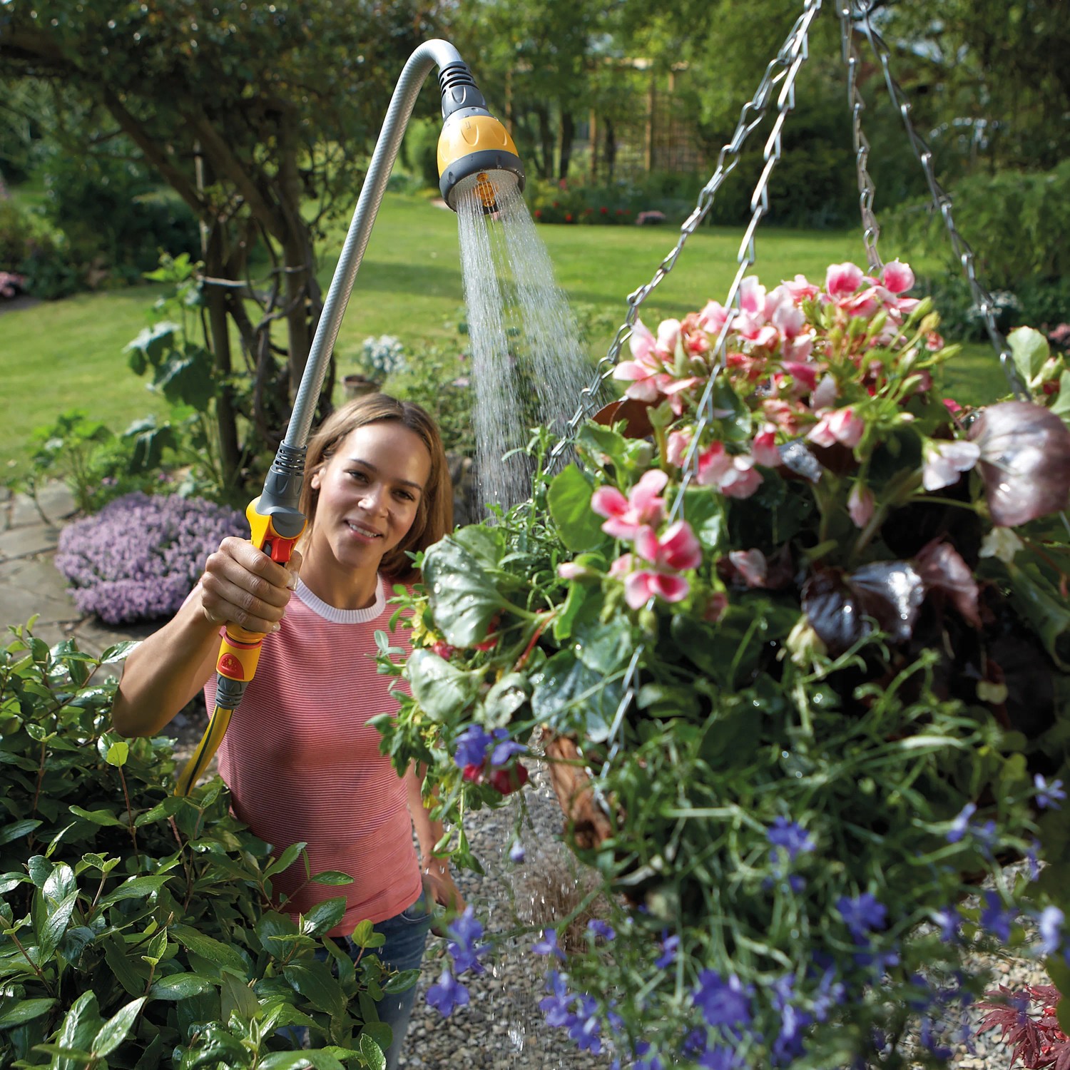 Frau bewässert Blumen mit Hozelock Flexi Spray 4in1 Gartenbrause.