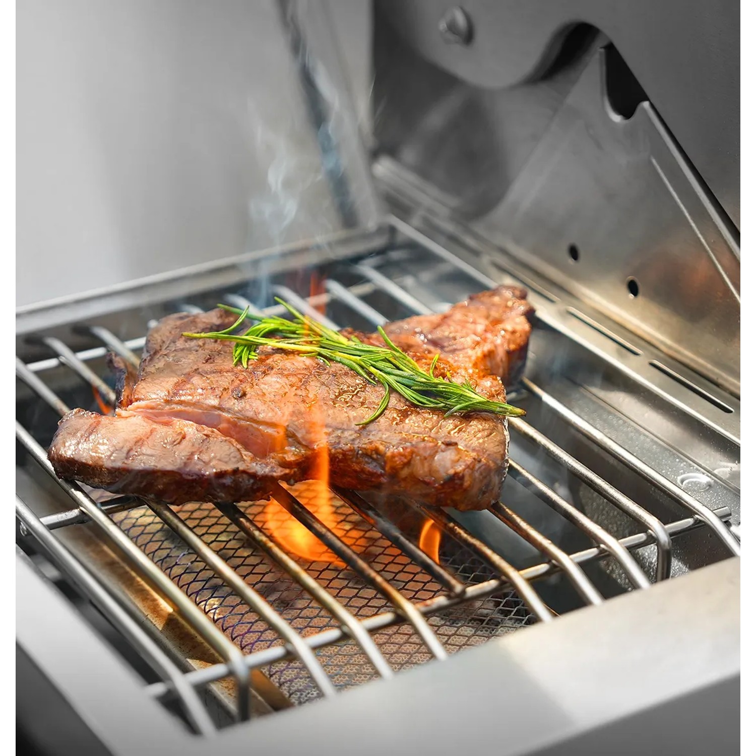 Saftiges Steak auf dem Taino Platinum Gasgrill mit Rosmarin, Flammen sichtbar.