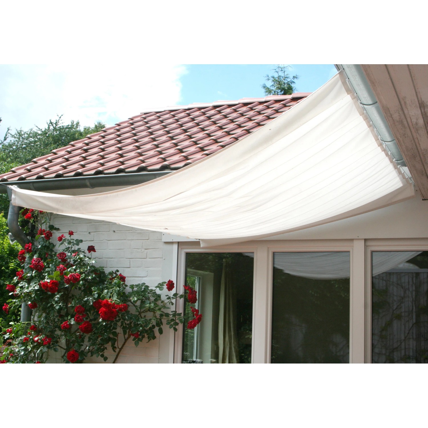 Weißes Peddy Shield Sonnensegel (330x200 cm) am Haus montiert. Ideal für Terrasse und Garten.