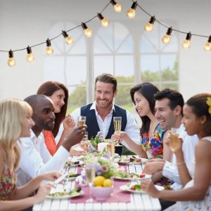 Gruppe feiert unter Partyzelt mit Lichterkette. Juskys Gartenzelt als Sonnenschutz.