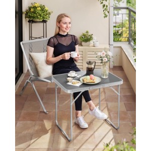 Grauer WOLTU Campingtisch Klapptisch aus Aluminium, zusammengeklappt mit Frau auf Balkon.