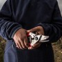 Felco 6 Gartenschere in Händen vor Weinberg. Einhand-Baumschere mit rotem Griff.