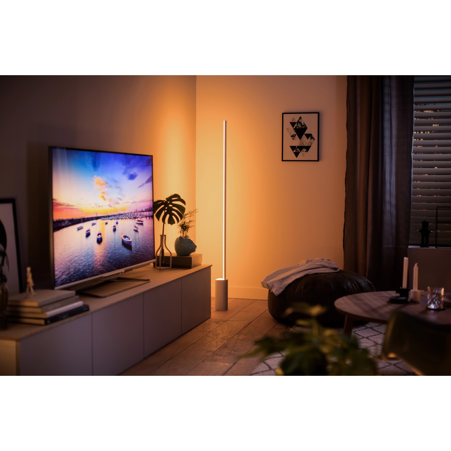 Weiße Philips Hue Gradient Signe Stehleuchte im Wohnzimmer mit Farbverlauf an der Wand.