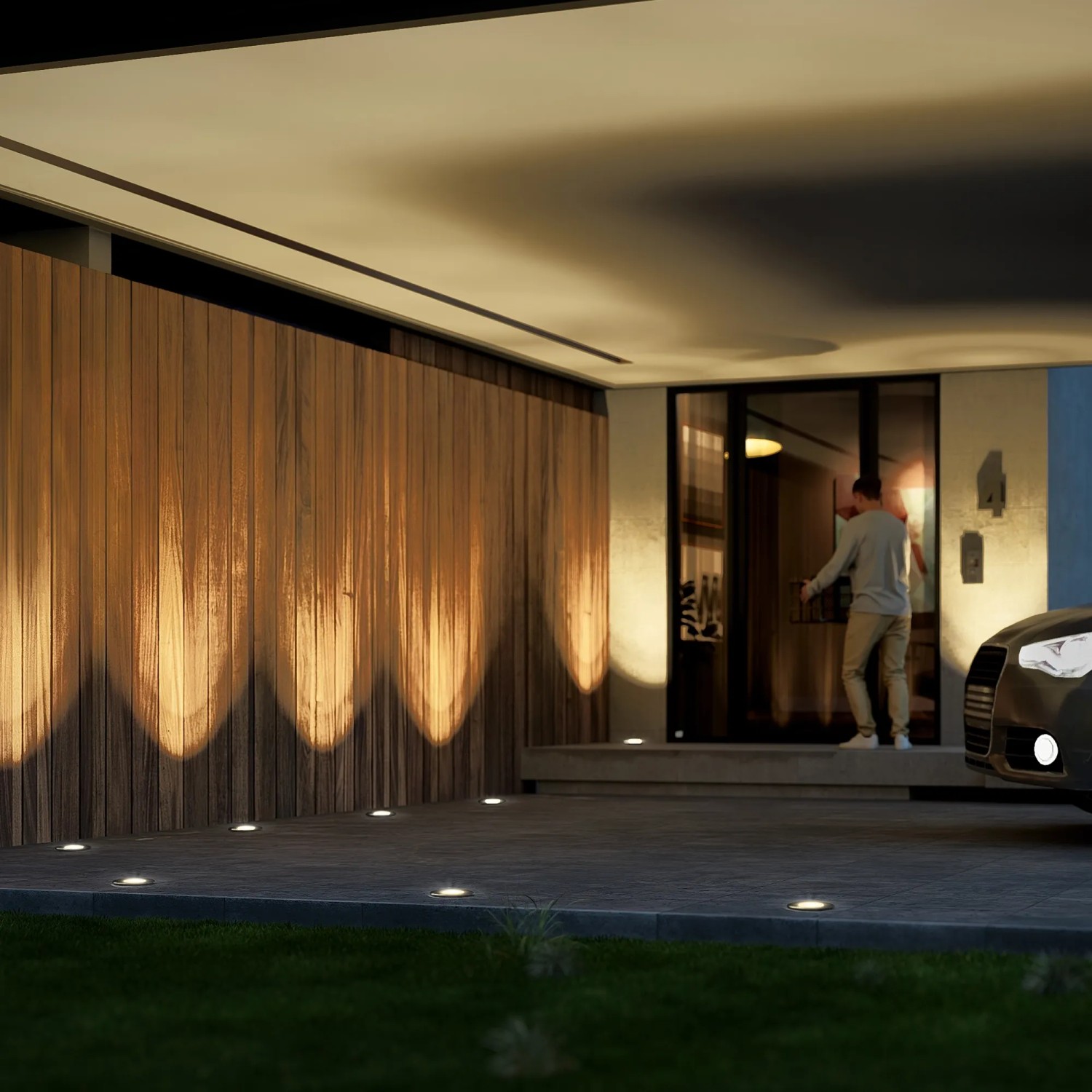 Eingebaute, schwarze SSC-LUXon Juavi Bodenleuchten beleuchten eine Hauswand und Einfahrt warmweiß.