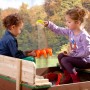 Axi Ella Sandkasten aus Holz mit zwei Kindern beim Spielen im Garten.