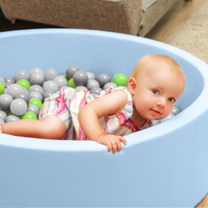 Baby im Bällebad mit grünen, grauen, weißen und transparenten LittleTom Bällen (Ø 5.5 cm).