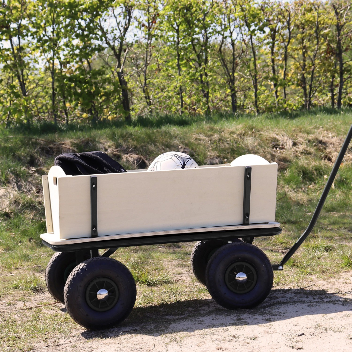 Schwarzer Sunny Bollerwagen Billy Beach Wagon mit Holzaufbau und Luftreifen im Gelände.