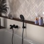 Schwarzes Schütte Handbrause-Set Raven mit Brauseschlauch an Badewanne.