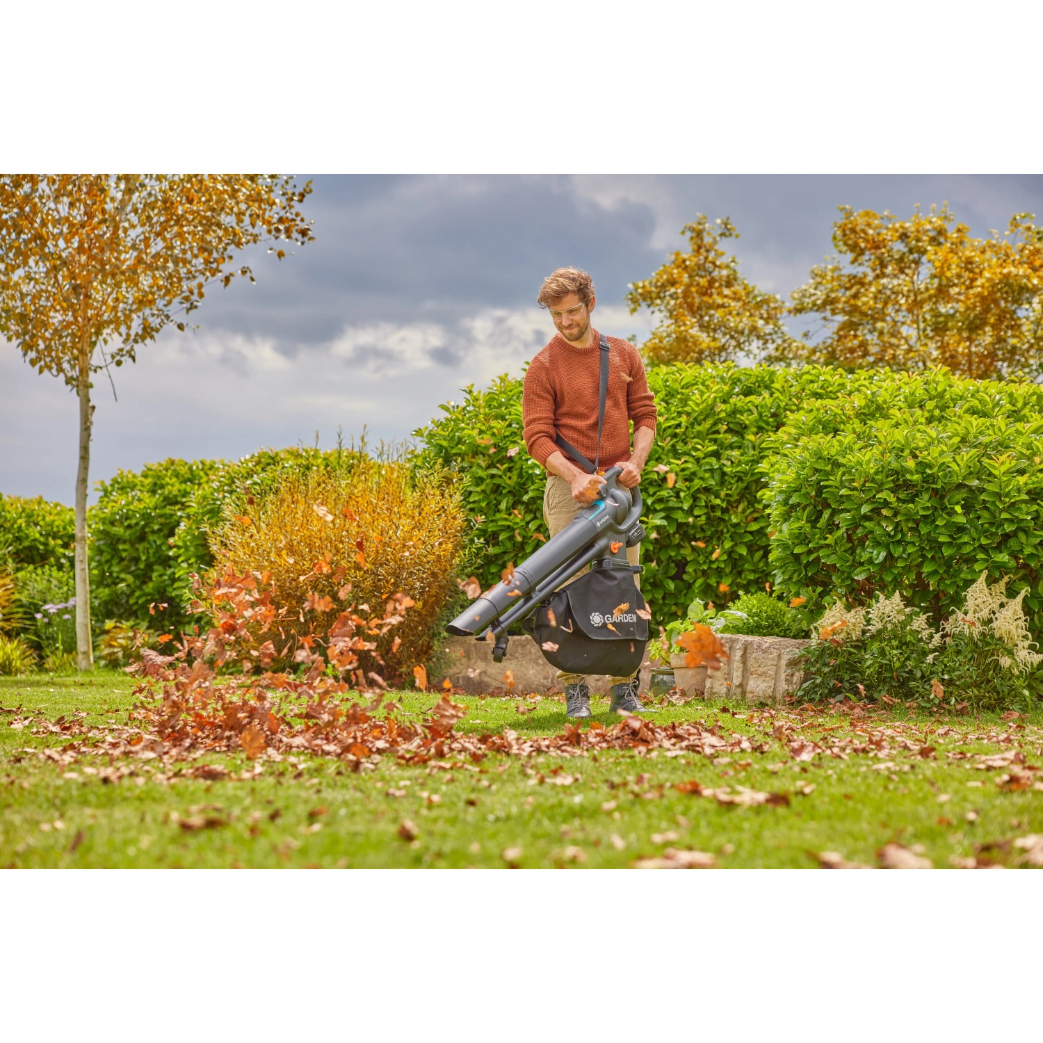 Gardena Akku-Laubsauger/-bläser PowerJetCollect Solo im Einsatz im Garten mit fallendem Laub.