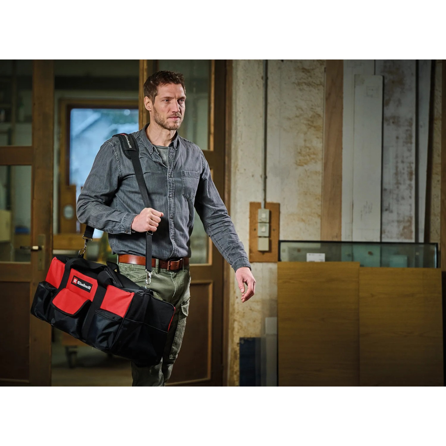 Einhell Werkzeugtasche (56cm) in Rot-Schwarz mit Tragegurt, getragen von einer Person.