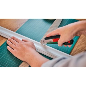 Bosch Cuttermesser im Einsatz: Schneiden einer Leiste mit Lineal auf einer Schneidematte.