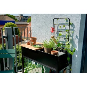 Juliana Urban Vertical Gewächshaus mit Arbeitsfläche und Rankgitter auf einem Balkon.