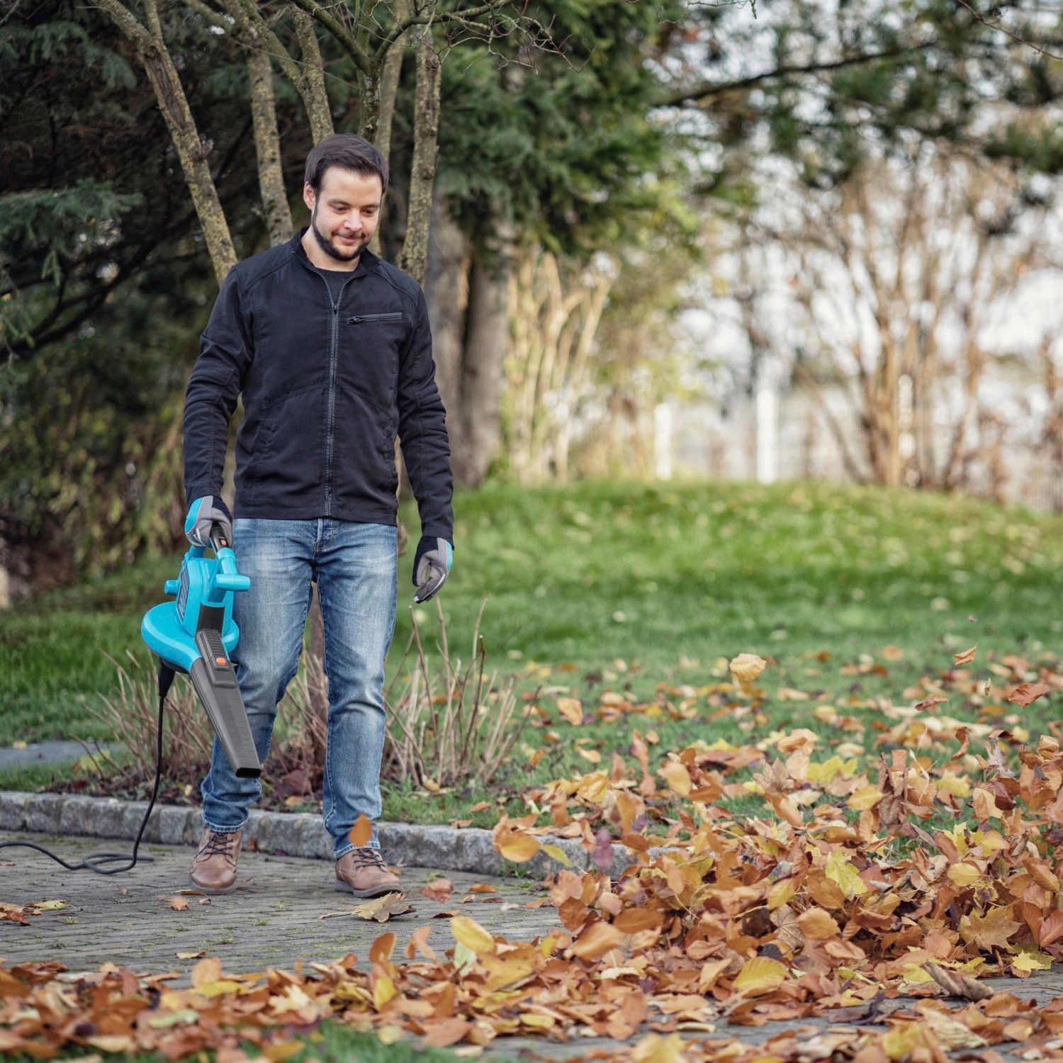 Mann nutzt Gardena Elektro-Laubbläser ErgoJet 3000 zum Laub entfernen.