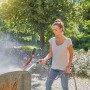 Frau reinigt Schubkarre mit Gardena Comfort Reinigungsspritze ecoPulse™ im Garten.