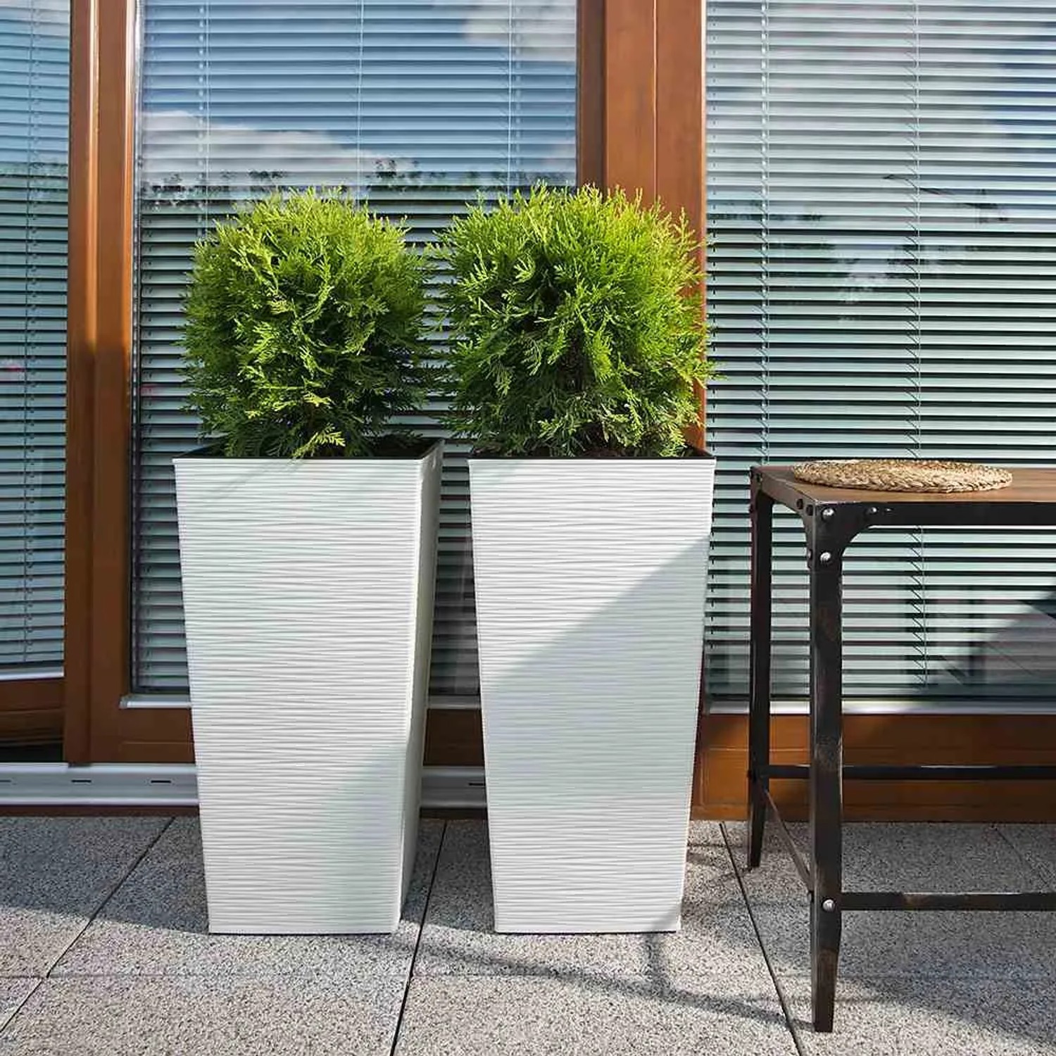 Zwei weiße Siena Garden Pflanzsäulen Nizza 35x35x68 cm mit Rillenoptik und Bepflanzung.