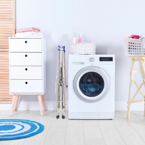 Zusammengeklappter Relaxdays XXL Wäscheständer aus silbernem Edelstahl auf Rollen neben einer Waschmaschine.