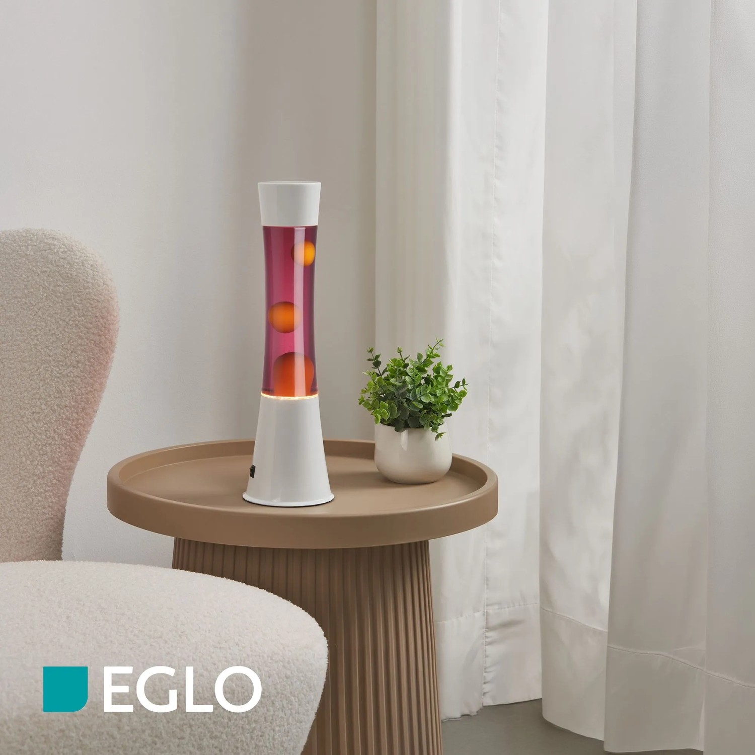 Eglo LED-Lavatischleuchte in Weiß mit bordeauxroter Flüssigkeit und orangefarbenem Wachs auf einem Beistelltisch.