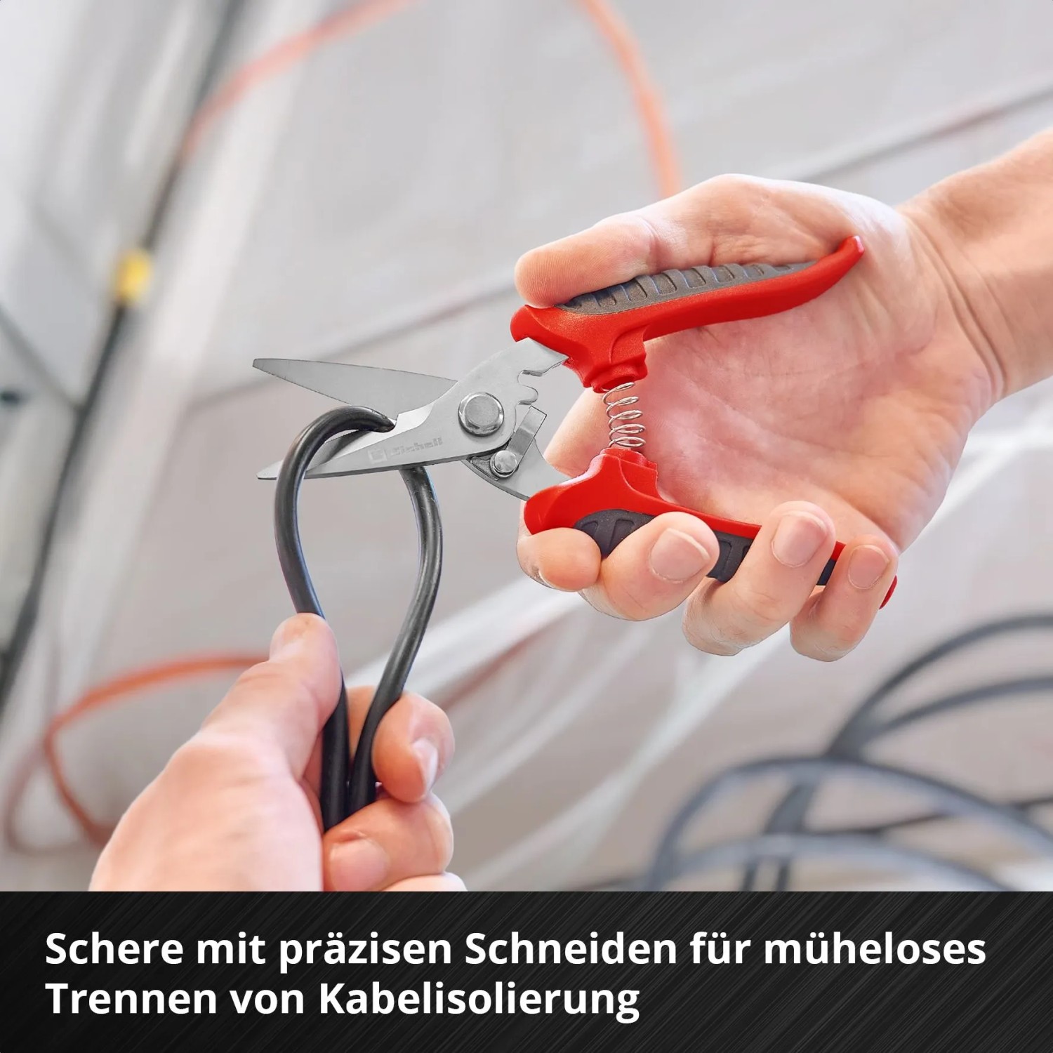Einhell Werkzeugkoffer: Hand schneidet Kabel mit einer Kabelschere. Teil eines 79-tlg. Werkzeug-Sets.