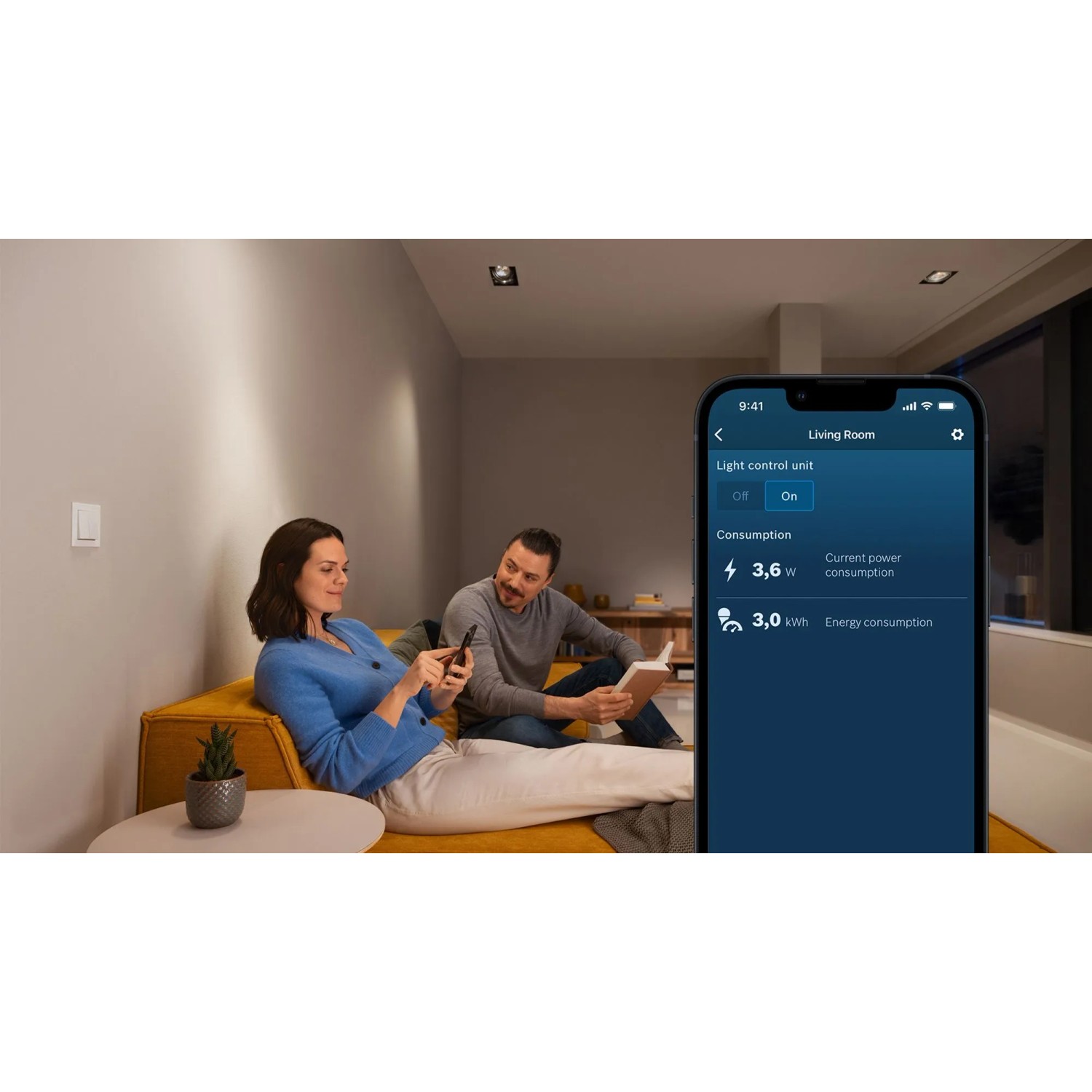 Paar steuert Bosch Smart Home Licht-/Rollladensteuerung per App im Wohnzimmer, zeigt Energieverbrauch.