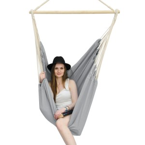 Grau-lila XXL Hängesessel: Frau sitzt entspannt in der Baumwoll-Hängematte mit Holzstab.