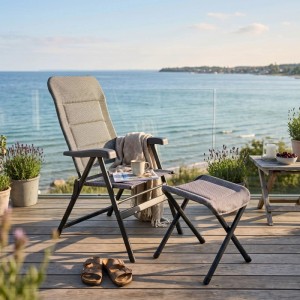 osoltus Alu Camping Hocker Open Grey, faltbar, mit Soft Touch Bezug, neben Klappsessel auf Terrasse am Meer.