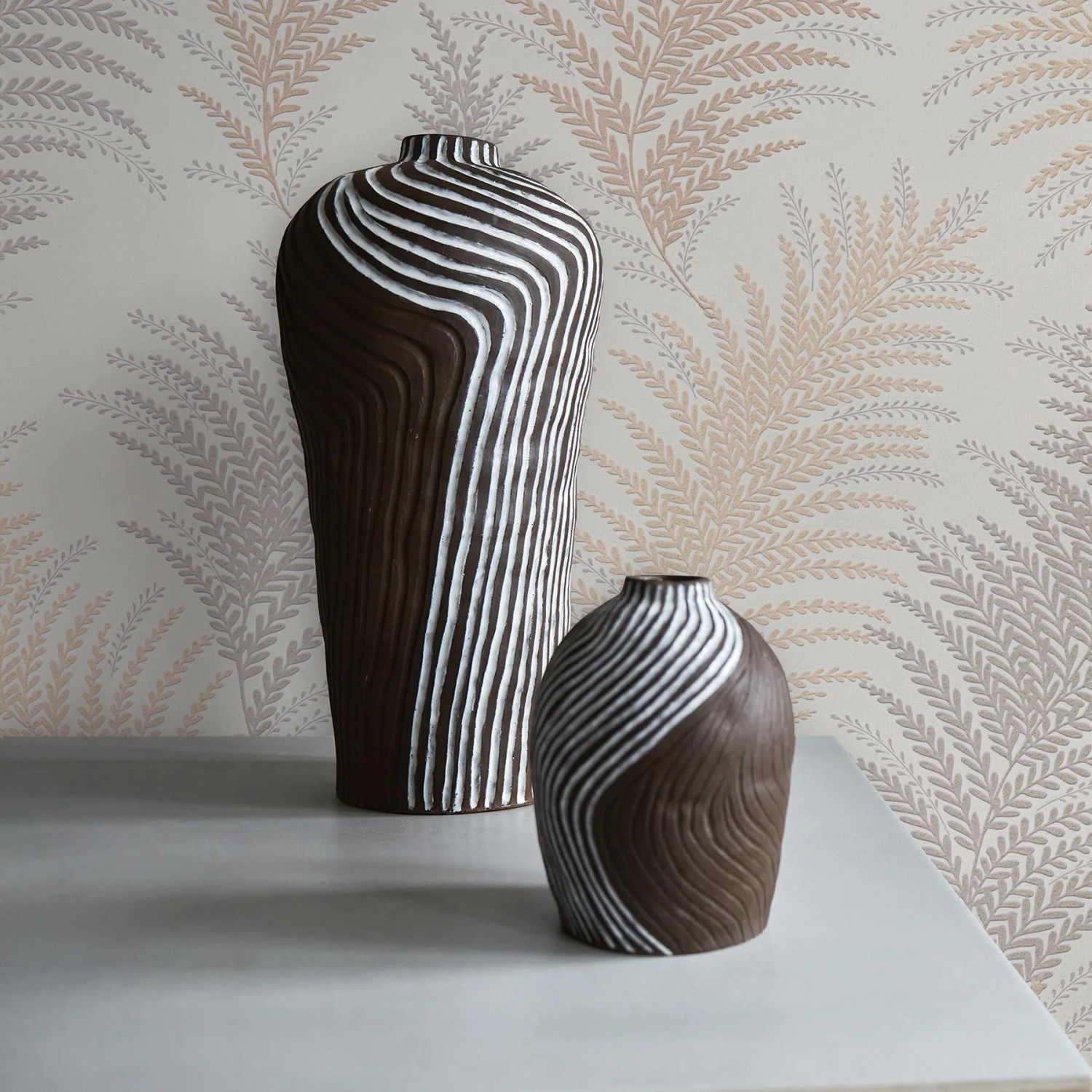 Tadessi Tapete Dschungel Ginevra: Beige-creme Papiertapete mit Naturmuster und zwei Vasen.