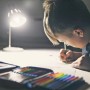 Kind malt im Licht einer Ledvance Sun@Home Smart+ Kerzenlampe. Biorhythmussteuerung für Wohlbefinden.