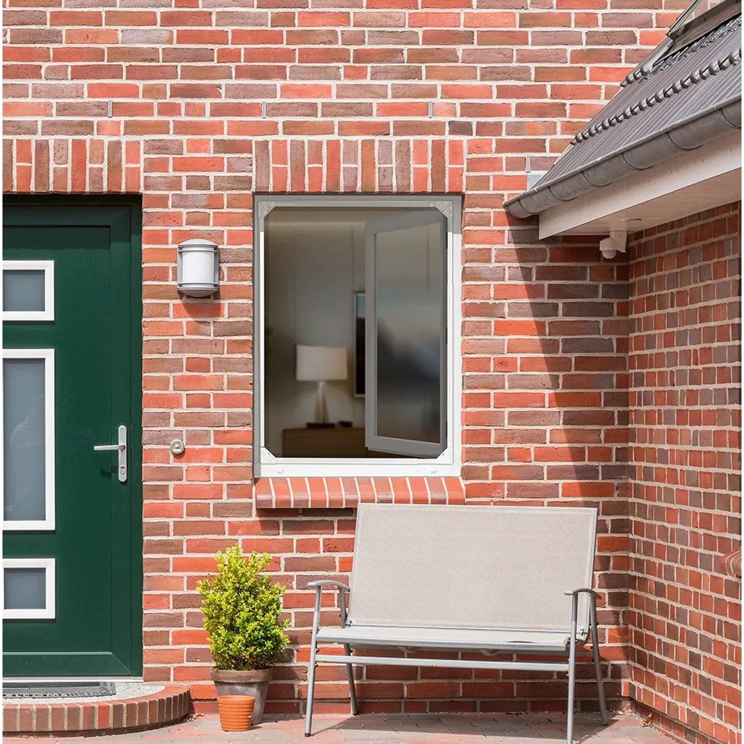 Weißes Easymaxx Fenster-Moskitonetz Magic Fit im Fensterrahmen eines Backsteinhauses.