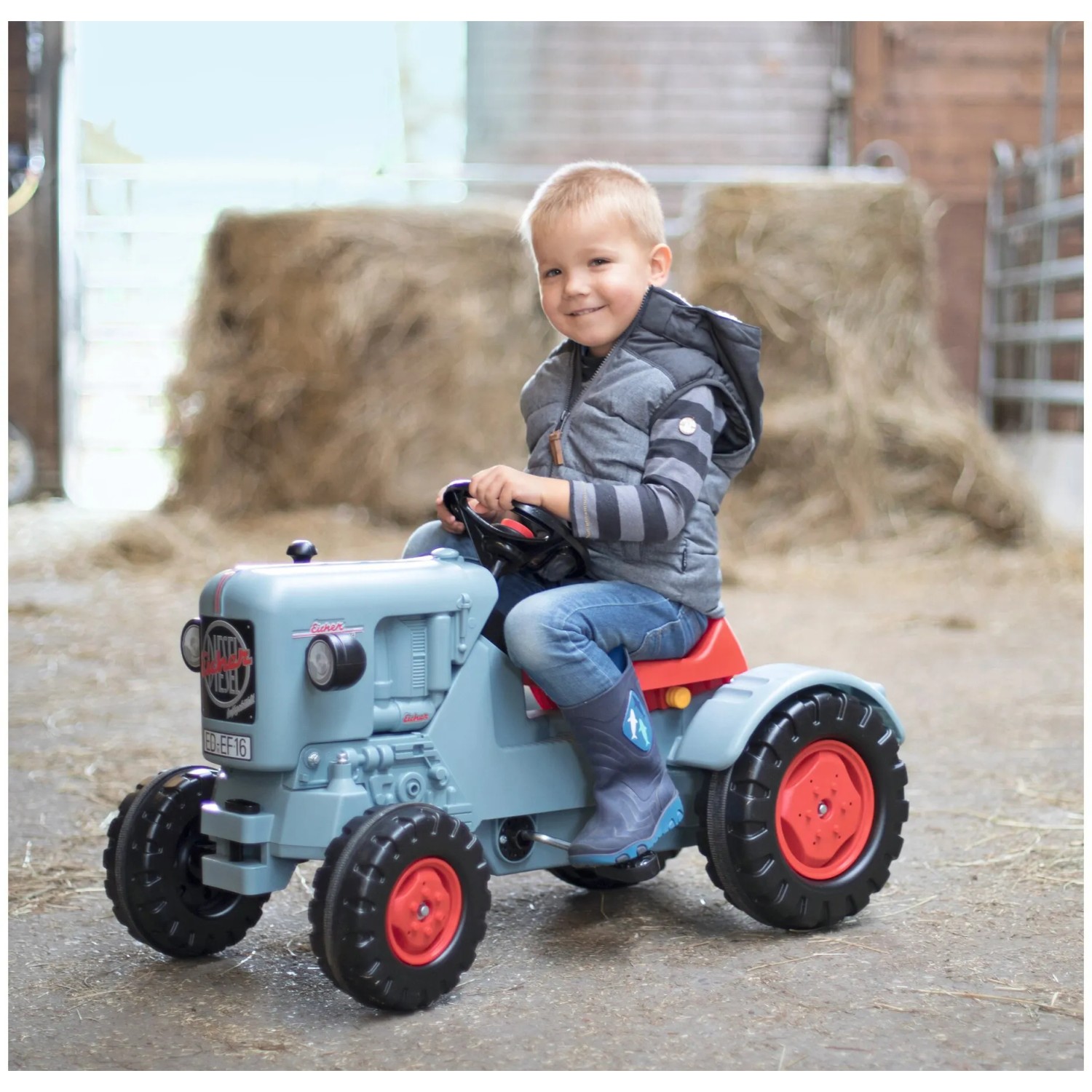 BIG Traktor Eicher Diesel ED 16 Trettraktor mit Kind auf dem Fahrersitz.