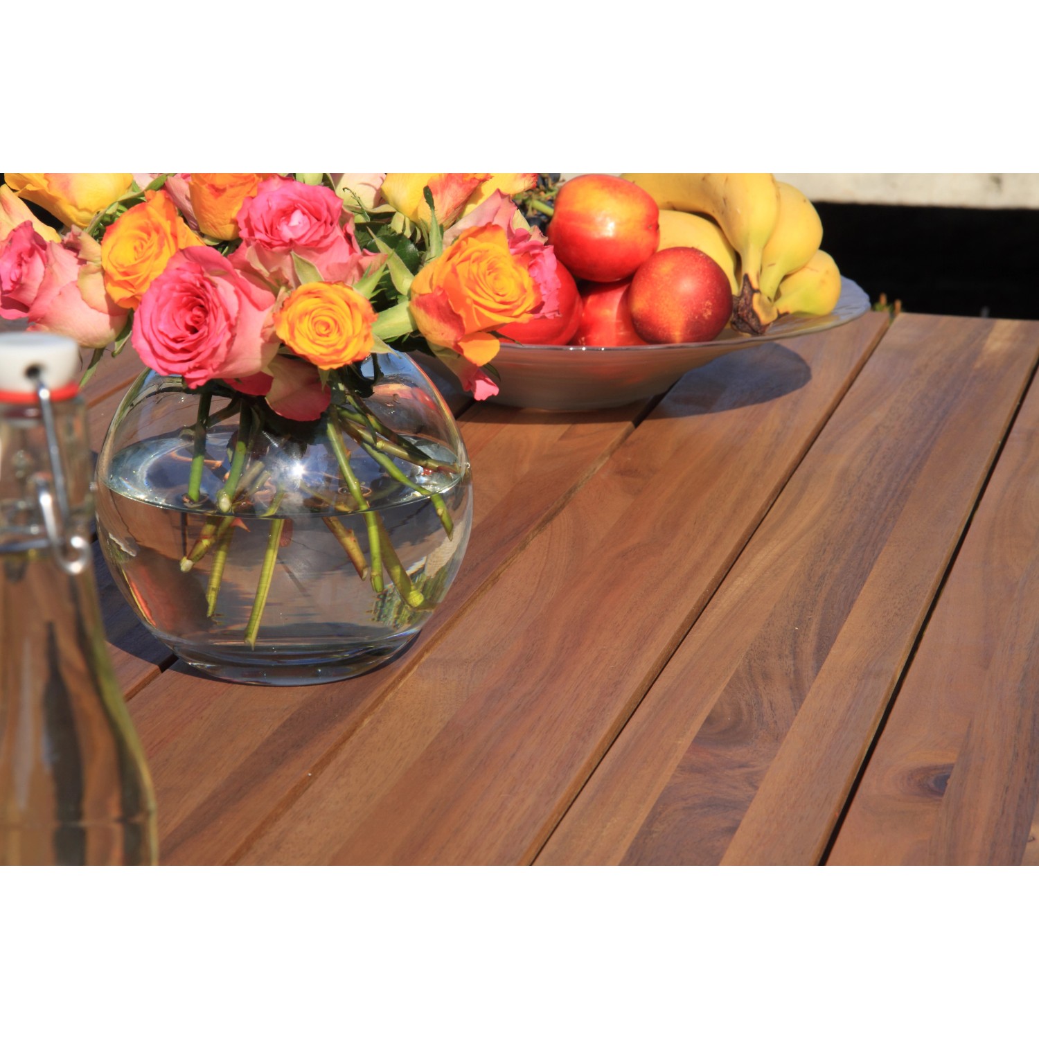 Detailansicht des Acamp Gartensets mit Teak-Tisch, Blumen und Obstschale.